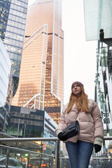Fototapeta na wymiar young woman next to skyscrapers and skyscrapers of a big city. tall business centers in the clouds in the background. bottom view