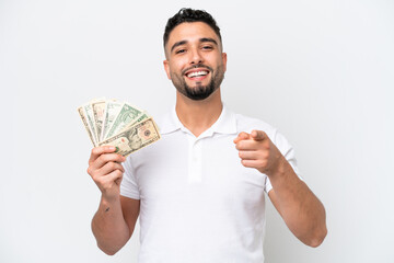 Young Arab man taking a lot of money isolated on white background surprised and pointing front