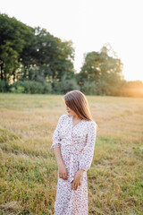 Fototapeta na wymiar Young woman with beautiful hair posing in field at sunset. Fashion, independence