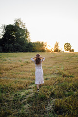 Young woman with beautiful hair posing in field at sunset. Fashion, independence