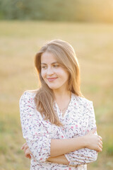 Fototapeta premium Young woman with beautiful hair posing in field at sunset. Fashion, independence