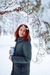 Fototapeta na wymiar Cheerful girl in warm clothes playing with snow outdoors near the beautiful forest