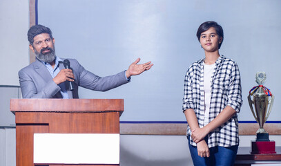 Young indian student girl appreciated and honored from the podium by professor in university college
