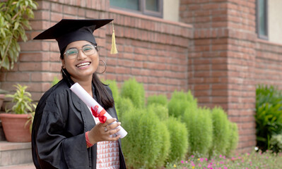 Happy young indian graduated girl holding graduation degree convocation ceremony. multiracial...