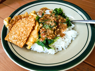 pecel rice with side dishes of tempeh and scrambled eggs