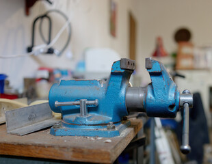 Side view of a blue bench vice 
on the workbench in a mechanical workshop