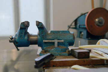 Side view of a blue bench vice 
on the workbench in a mechanical workshop