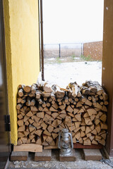 The firewood on the snowy porch of the house is harvested for the winter. Heating of housing with a stove fireplace, saving electricity and gas in a crisis, environmental friendliness.