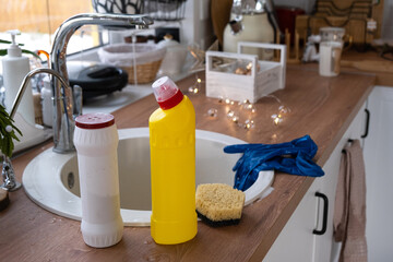 Fototapeta na wymiar Cleaning the kitchen before the Christmas and New Year holidays. Detergent, dry powder, sponge, gloves are on the sink. Festive decor in the white kitchen, cozy interior of the home