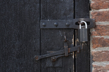 An old wooden door locked with a padlock
