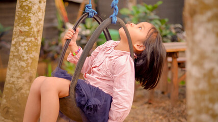 Portrait dreamy funny little girl riding on swing in the twilight with nature background