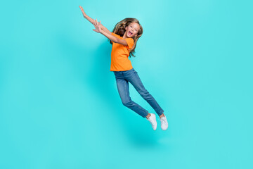 Fototapeta na wymiar Full length photo of young funky cute schoolgirl blonde hair hands up jumping high trampoline celebrate her vacation time isolated on aquamarine color background