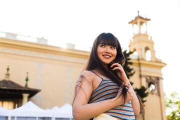 Asian european young woman in the streets of Barcelona, Spain. She is brunette, with a fringe haircut and wears summer clothes