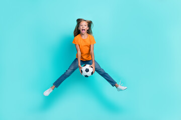 Full length size photo of young preteen schoolkid girl wear orange t-shirt denim jeans jump trampoline hold ball carefree isolated on cyan color background