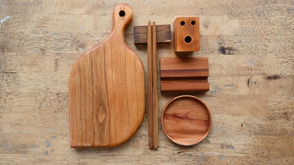 Wooden chopping board, wooden chopsticks, teak wood coaster and wooden phone holder on wooden table