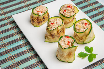 Grilled zucchini rolls with curd cheese and tuna on plate.