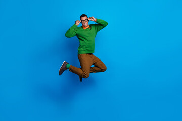 Fototapeta na wymiar Full body length photo of young excited positive gentleman guy jumping air hold his eyeglasses celebrate weekend isolated on blue color background