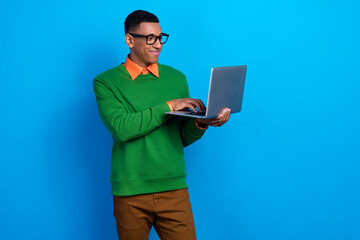 Portrait of positive cheerful guy orange shirt under green pullover hold laptop writing program...