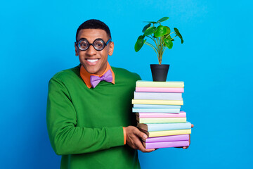 Photo of young silly guy wear funny green jumper new stupid eyeglasses hold stack books relocation...