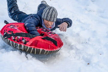 Fototapeta na wymiar Young boy rides on tubing in snow at winter.