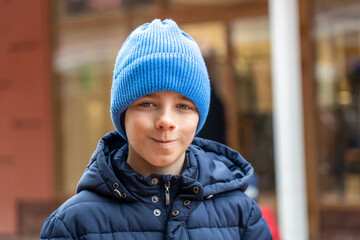Portrait of smiling teenage boy in blue hat on street outdoors