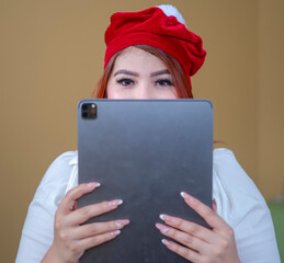 beautiful woman looking at christmas shopping on tablet wearing a christmas hat