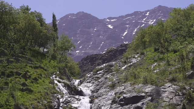 Landscape Waterfall and Toubkal view in Imlil, Morocco with rocky mountains on the horizon