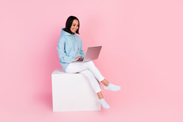 Full length photo of adorable sweet girl dressed blue sweatshirt working modern gadget empty space isolated pink color background - Powered by Adobe