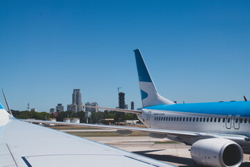 The tail end of a large airplane, parked at the gate, with the city of Buenos Aires in the background. 