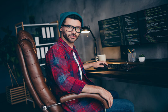 Photo of clever positive coder dressed hat glasses creating web design modern gadget indoors workplace workstation loft