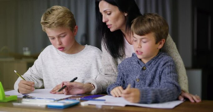 Mother help boys, with homework and for learning to assist with studying or education. Mama, sons and homeschool for teaching, child development or students writing in books, talking or reading notes