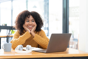 Photo of cheerful joyful mixed-race woman in yellow shirt smiling work on laptop talk speak video...