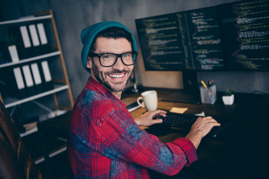 Photo of cheerful happy freelancer wear hat glasses smiling working modern gadget service indoors workplace workstation loft