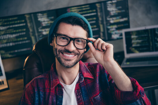 Photo of good mood funny freelancer wear hat glasses smiling writing software indoors workplace workstation loft