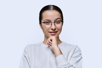 Teenage girl in glasses looking at camera on white studio background