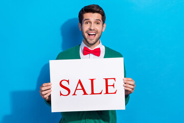 Photo of astonished shocked man showing holding paper card offer proposition information low prices isolated on blue color background