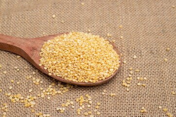 Closeup of Moong Dal or Green Gram Beans in a Wooden Ladle Isolated on Burlap Background