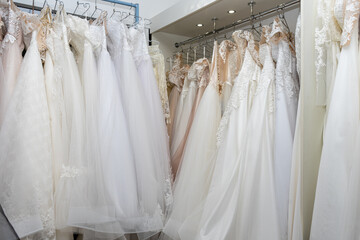 White and cream wedding dresses on a hanger in a bridal boutique. Close up