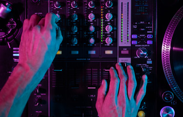 Club DJ mixing music with sound mixer device. Overhead photo of disc jockey playing set on party in...