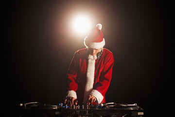 Santa DJ plays Christmas music set on party. Club disc jockey mixing musical tracks on New Years...