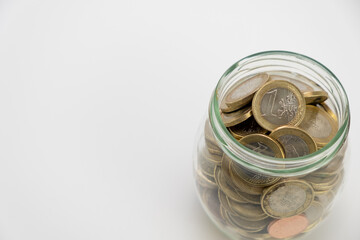 Glass jar full until the top with euro coins, centered on a white background, top view. One euro coins saving concept. Copy space.