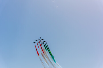 Aerobatic maneuver during Frecce Tricolori air show under a blue sky