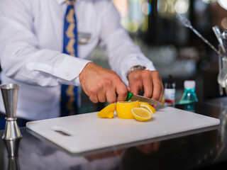 a bartender cutting a lemon for a cocktail