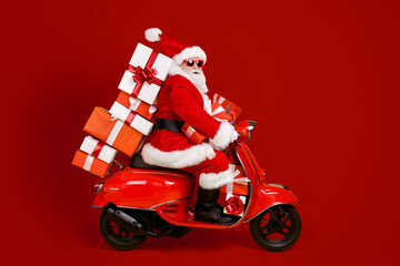 Profile side view of his he nice funny cheery white-haired St Nicholas riding moped hurry up rush delivering bringing pile stack giftboxes isolated bright vivid shine vibrant yellow color background © deagreez