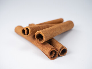 Cinnamon sticks lie neatly stacked on a white background. Cinnamon sticks evoke associations with winter and the new year. Close-up cinnamon concept.