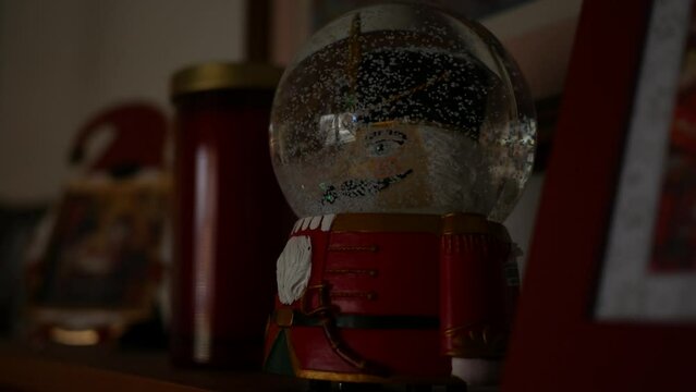 Man puts a nutcracker snowglobe on the shelf around Christmas Time
