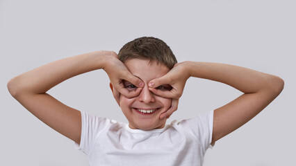 Boy looking through binoculars gesture at camera