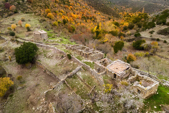 Aerial view of derelict stone farm buildings at Maltiola near the Col de San Colombano in Corsica surrounded by autumnal trees