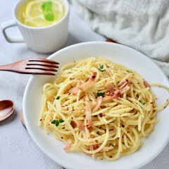 A tantalizing plate of bacon aglio e olio: spaghetti tossed in garlic-infused olive oil, adorned with crispy bacon and dried chili flakes—a spicy twist on a savory Italian classic.