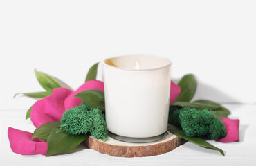 burning scented candle in white glass with rose petal and green leaves decor. stylish house decoration, details of cozy home 